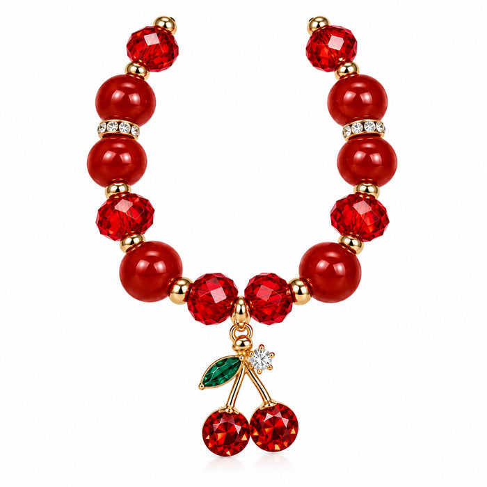 A red beaded necklace featuring faceted red beads, gold-toned spacer rings with clear rhinestones, and a cherry charm at the center with a green leaf and red crystal cherries.